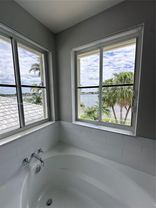 bathroom featuring plenty of natural light, a bathing tub, and a water view