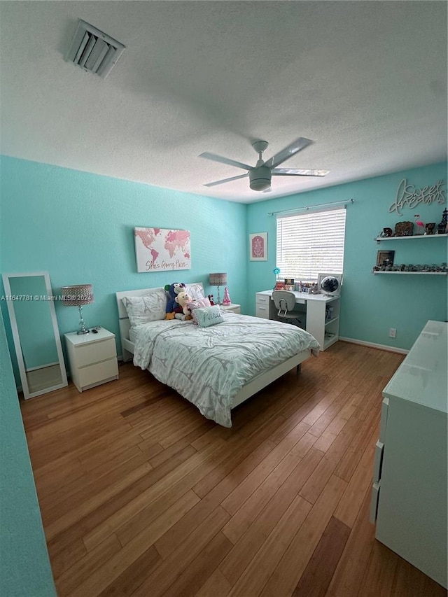 bedroom with a textured ceiling, ceiling fan, and wood-type flooring