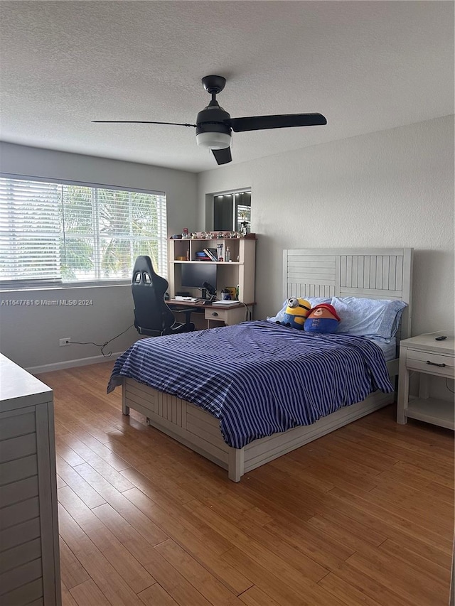 bedroom with a textured ceiling, ceiling fan, and wood-type flooring