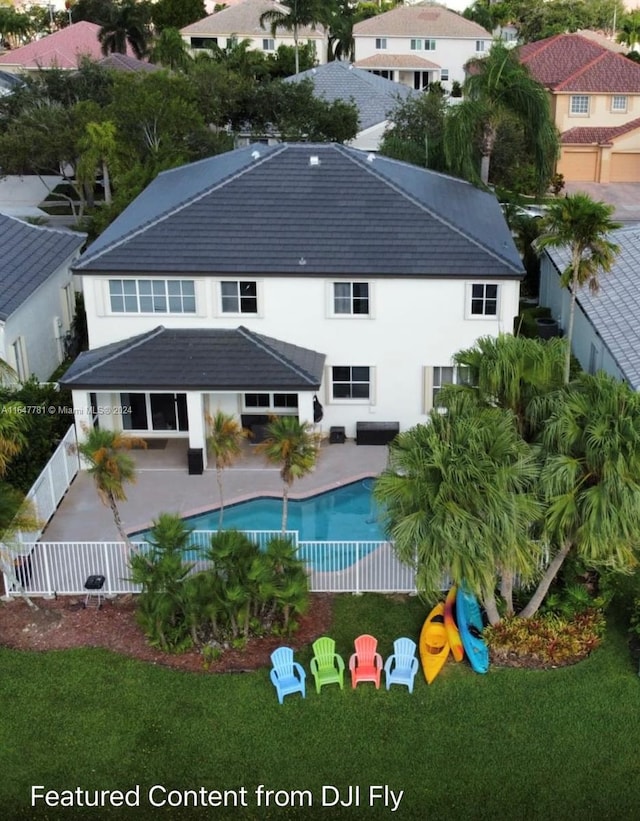 rear view of house with a fenced in pool, a patio area, and a lawn