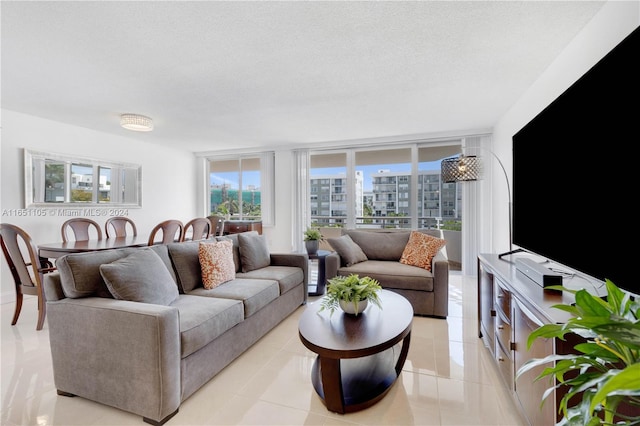 living room featuring a textured ceiling, light tile patterned floors, and expansive windows