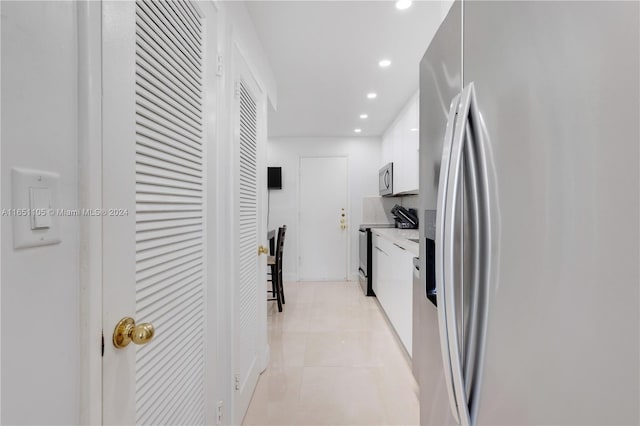 kitchen with light tile patterned flooring, stainless steel appliances, and white cabinets