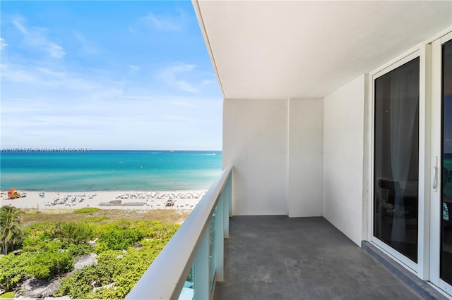 balcony featuring a view of the beach and a water view