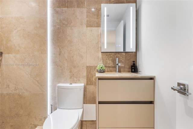 bathroom with tile walls, toilet, and vanity