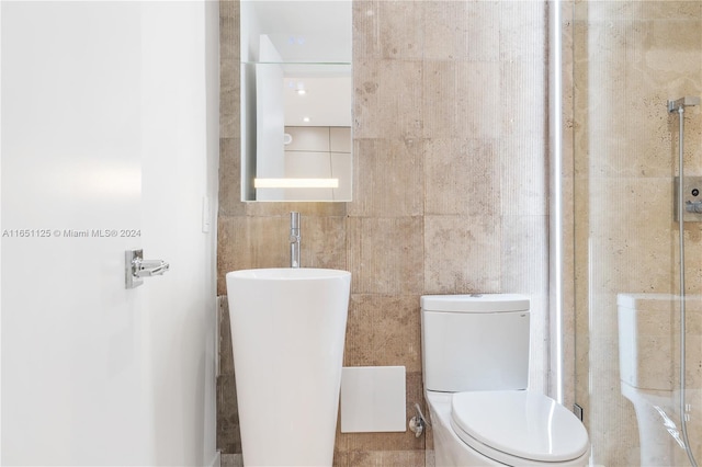 bathroom featuring tile walls and toilet