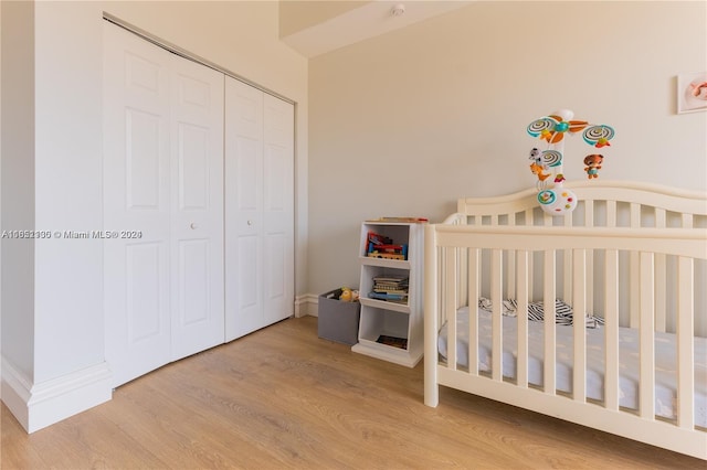 bedroom featuring a crib, hardwood / wood-style floors, and a closet