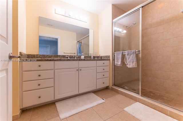 bathroom with tile patterned flooring, vanity, and a shower with door