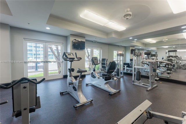 gym with french doors and a tray ceiling