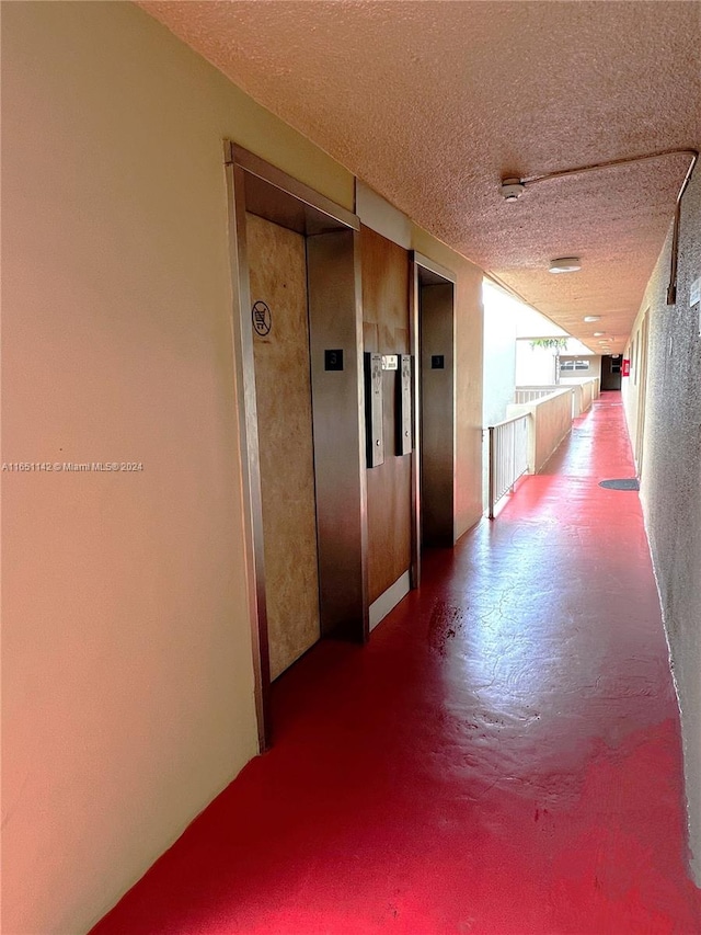 hallway with a textured ceiling and elevator