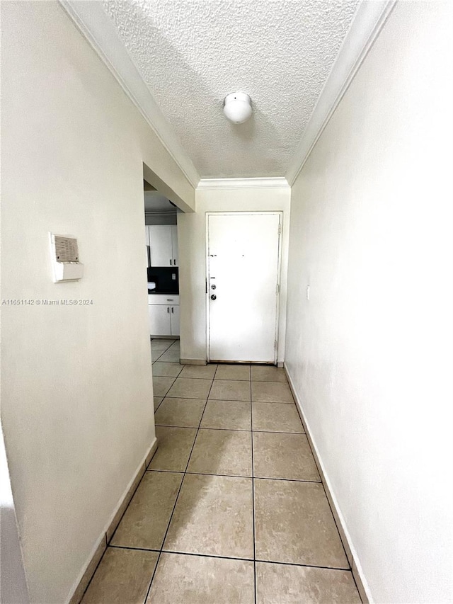 corridor with a textured ceiling, crown molding, and light tile patterned floors