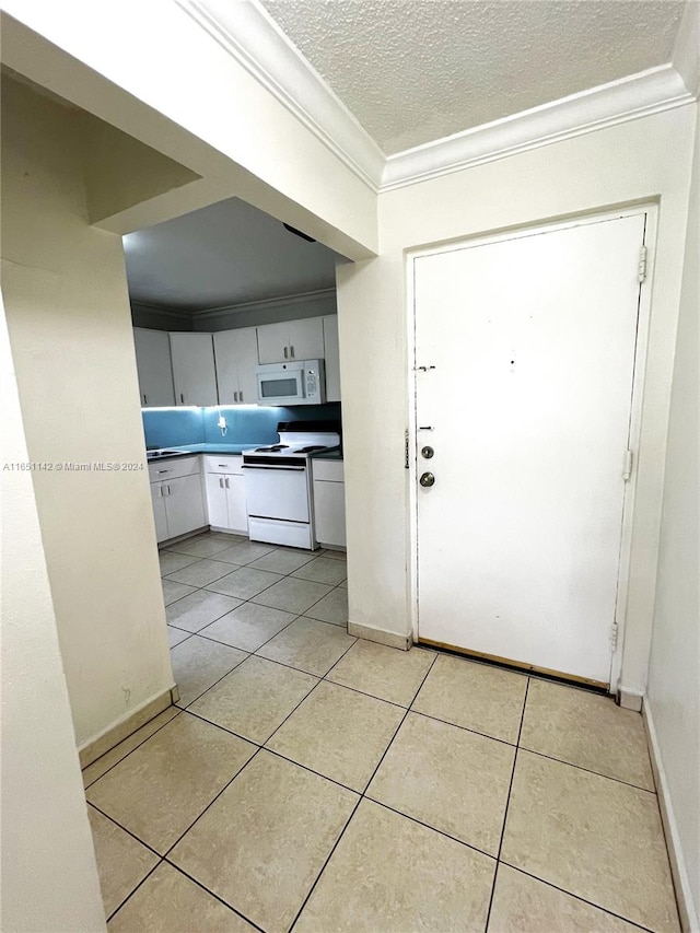 kitchen with a textured ceiling, white appliances, light tile patterned floors, crown molding, and white cabinetry