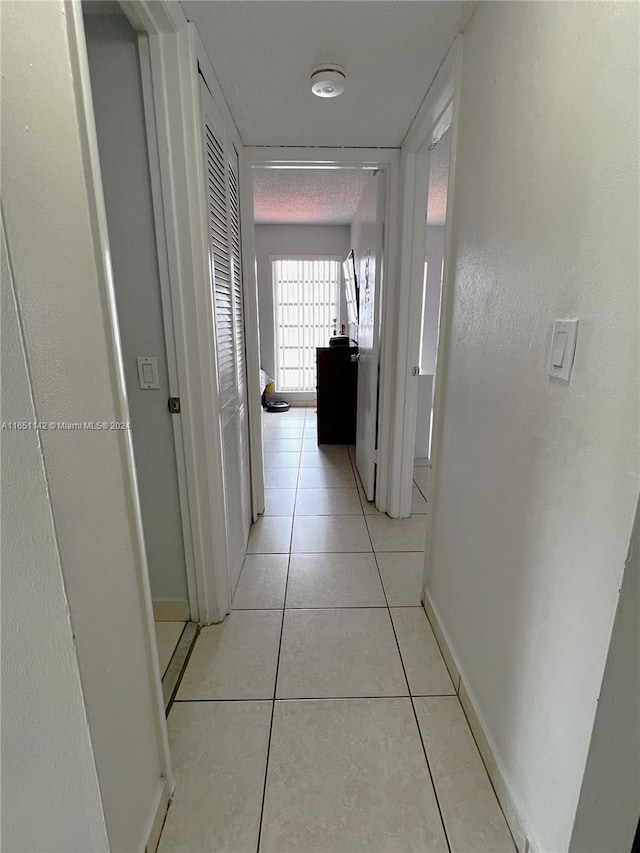 hall with light tile patterned floors and a textured ceiling