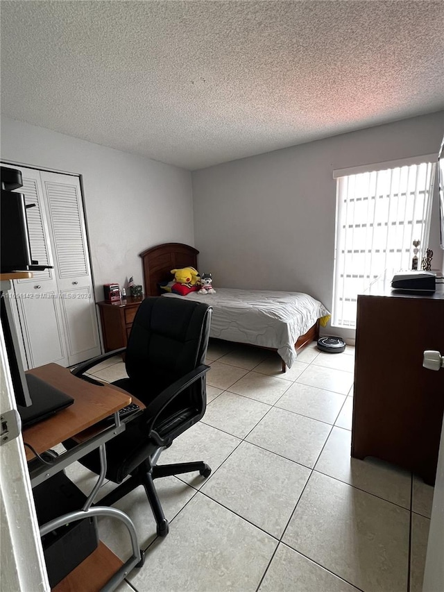 tiled bedroom with a closet and a textured ceiling