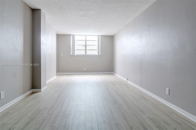 spare room with light hardwood / wood-style floors and a textured ceiling