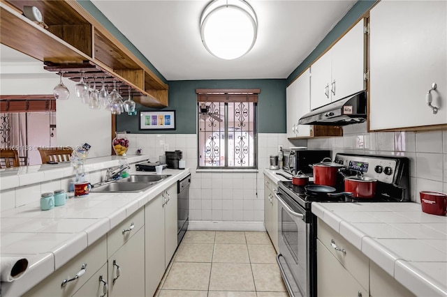 kitchen with sink, electric stove, tile countertops, dishwasher, and white cabinetry