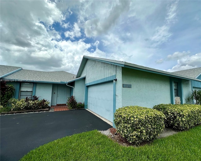 23304 SW 58th Ave Unit B, Boca Raton, FL 33428 - view of property exterior with a garage, asphalt driveway, stucco siding, and roof with shingles
