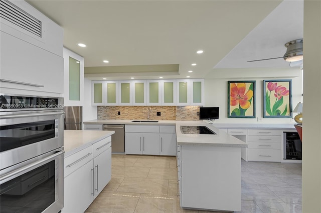 kitchen with a kitchen island, white cabinetry, stainless steel appliances, wine cooler, and sink