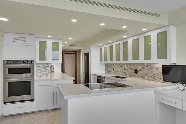 kitchen featuring white cabinetry, kitchen peninsula, stainless steel appliances, tasteful backsplash, and sink