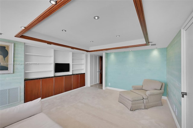 living area with built in shelves, light carpet, and a raised ceiling