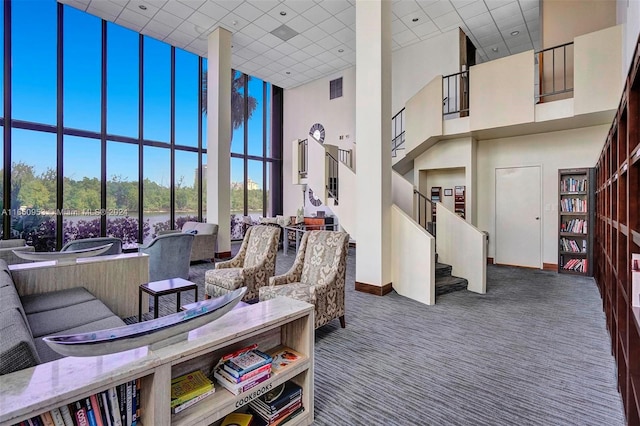 carpeted living room featuring floor to ceiling windows and a towering ceiling