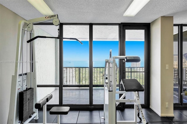 workout area featuring a textured ceiling, expansive windows, and a water view