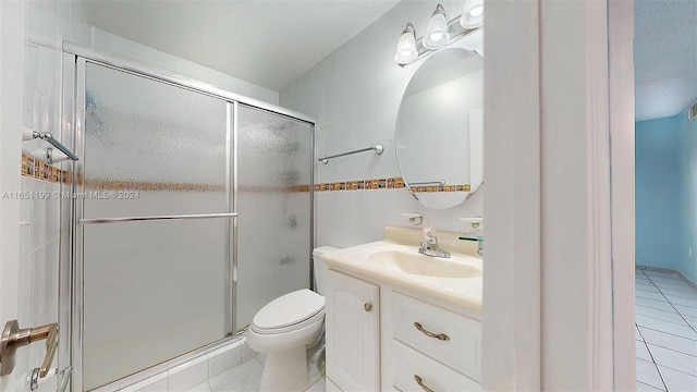 bathroom with vanity, tile patterned flooring, toilet, and a shower with door