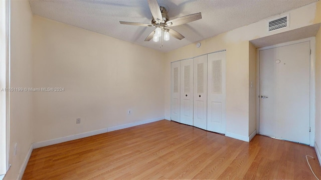 unfurnished bedroom with a textured ceiling, ceiling fan, a closet, and light hardwood / wood-style flooring