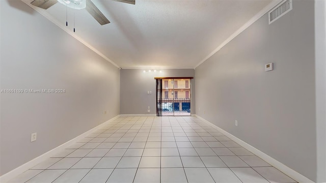 tiled spare room featuring crown molding and ceiling fan