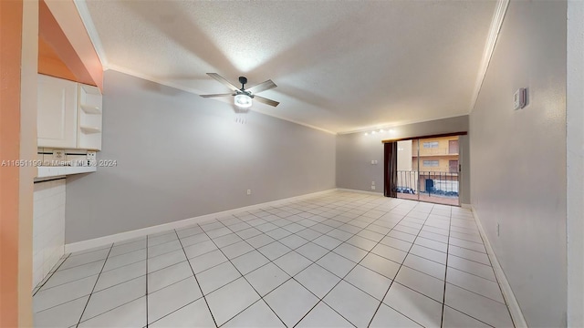 tiled empty room with ceiling fan, a textured ceiling, and ornamental molding