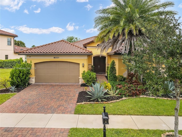 mediterranean / spanish-style house with a garage and a front lawn