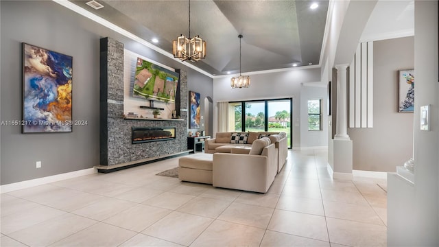 tiled living room featuring a textured ceiling, a raised ceiling, a notable chandelier, ornate columns, and a large fireplace