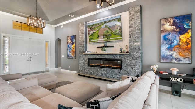 tiled living room with crown molding, a stone fireplace, high vaulted ceiling, and a chandelier