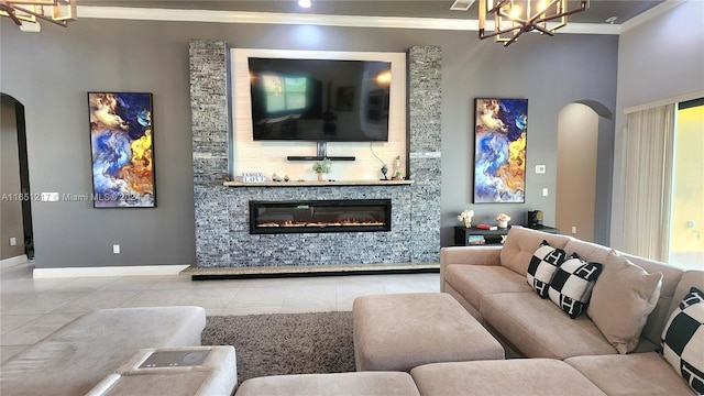 living room featuring light tile patterned floors, ornamental molding, a notable chandelier, and a stone fireplace