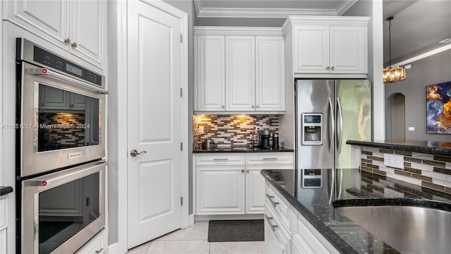 kitchen with appliances with stainless steel finishes, dark stone countertops, tasteful backsplash, and ornamental molding