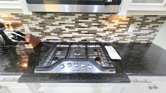 room details featuring stainless steel appliances, dark stone counters, backsplash, and white cabinetry