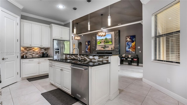 kitchen with crown molding, white cabinetry, decorative light fixtures, decorative backsplash, and a center island with sink