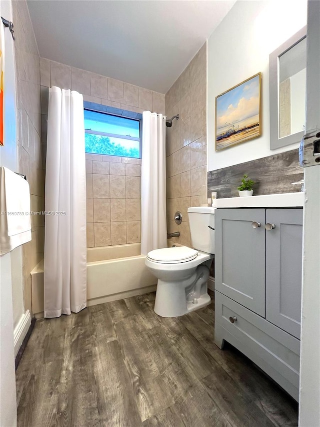 full bathroom with tile walls, hardwood / wood-style floors, toilet, shower / bath combination with curtain, and vanity