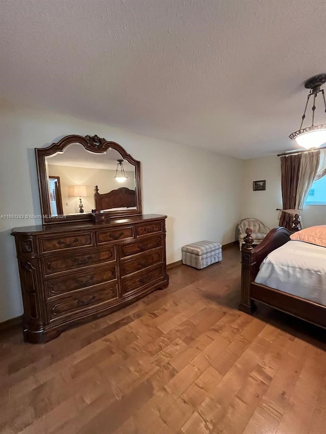 bedroom with light wood-type flooring, baseboards, and a textured ceiling