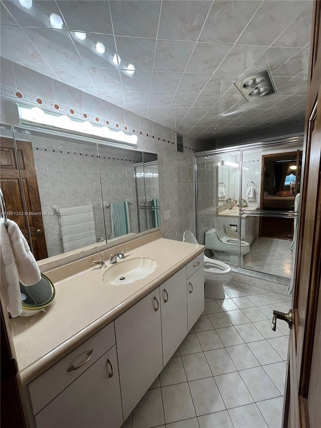 full bathroom featuring a stall shower, toilet, tile patterned floors, vanity, and tile walls