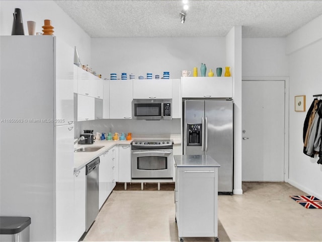 kitchen with appliances with stainless steel finishes, sink, a textured ceiling, and white cabinets