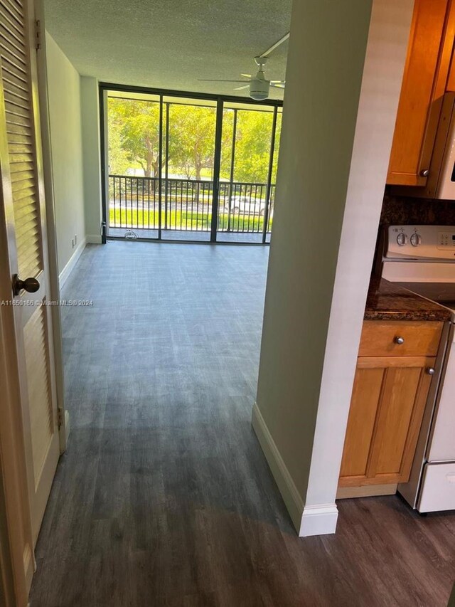 3475 N Country Club Dr Unit 204, Aventura, FL 33180 - hall featuring a wall of windows, dark wood-style flooring, baseboards, and a textured ceiling