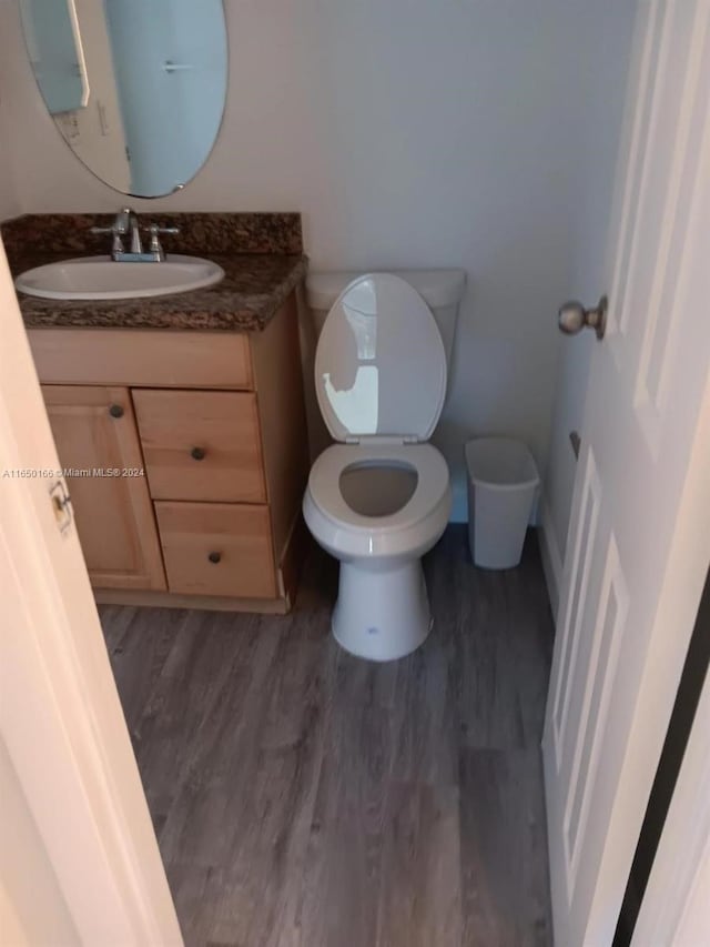 bathroom with vanity, toilet, and hardwood / wood-style floors