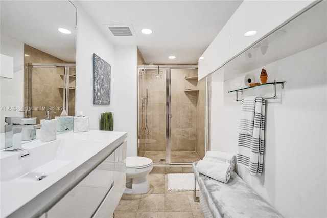 bathroom featuring tile patterned floors, toilet, a shower with door, and vanity