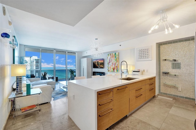 kitchen with an inviting chandelier, kitchen peninsula, sink, expansive windows, and a water view