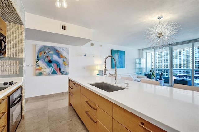 kitchen with black appliances, hanging light fixtures, a notable chandelier, and sink