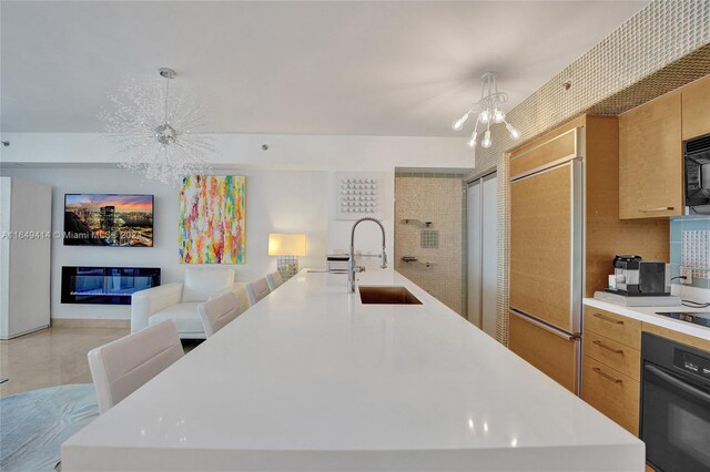 kitchen featuring black appliances, pendant lighting, a notable chandelier, and sink