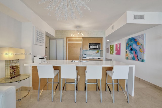 kitchen with an inviting chandelier, sink, black appliances, an island with sink, and a kitchen breakfast bar