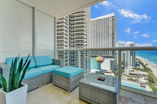 balcony with outdoor lounge area, a view of the beach, and a water view