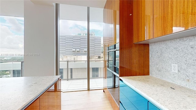 kitchen with a wealth of natural light, decorative backsplash, and light hardwood / wood-style floors