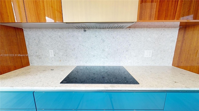 details featuring black electric stovetop, exhaust hood, light stone countertops, and backsplash